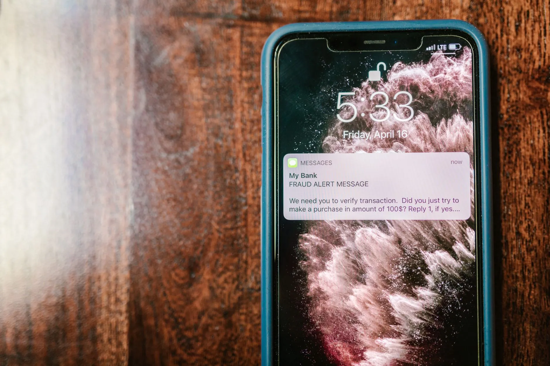 Celular sobre a mesa exibindo uma mensagem de alerta de fraude do banco
