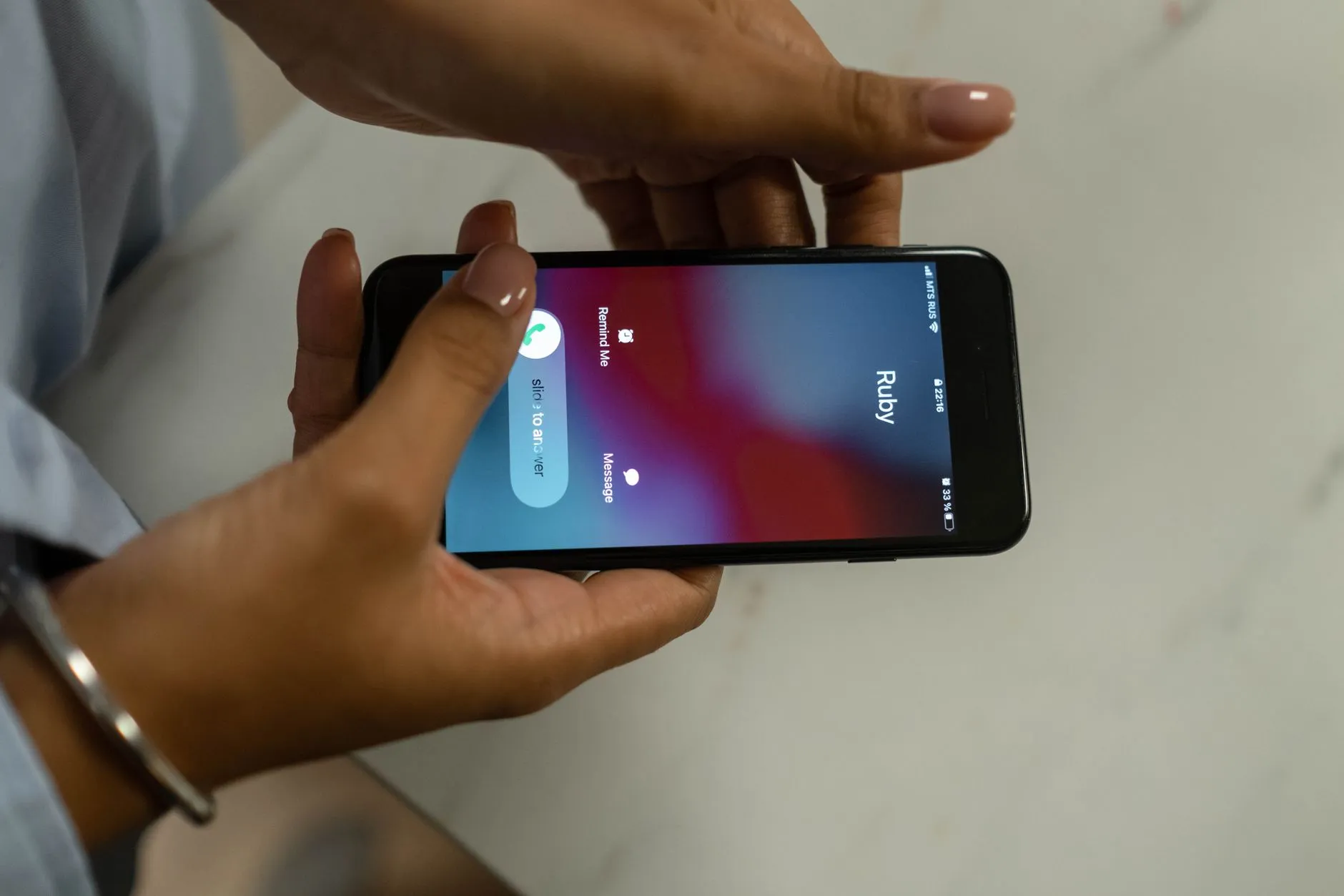 Mãos segurando um celular que recebe uma ligação, com as opções de atender ou recusar na tela