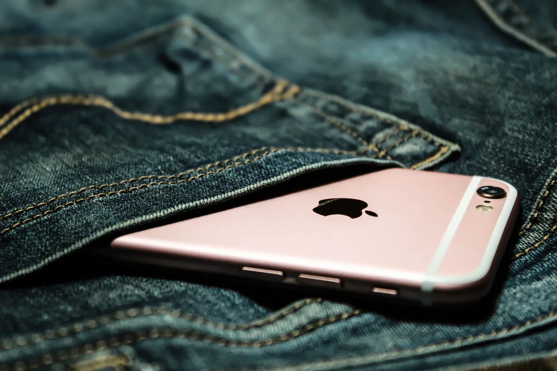 Celular rosa saindo do bolso de trás de uma calça jeans
