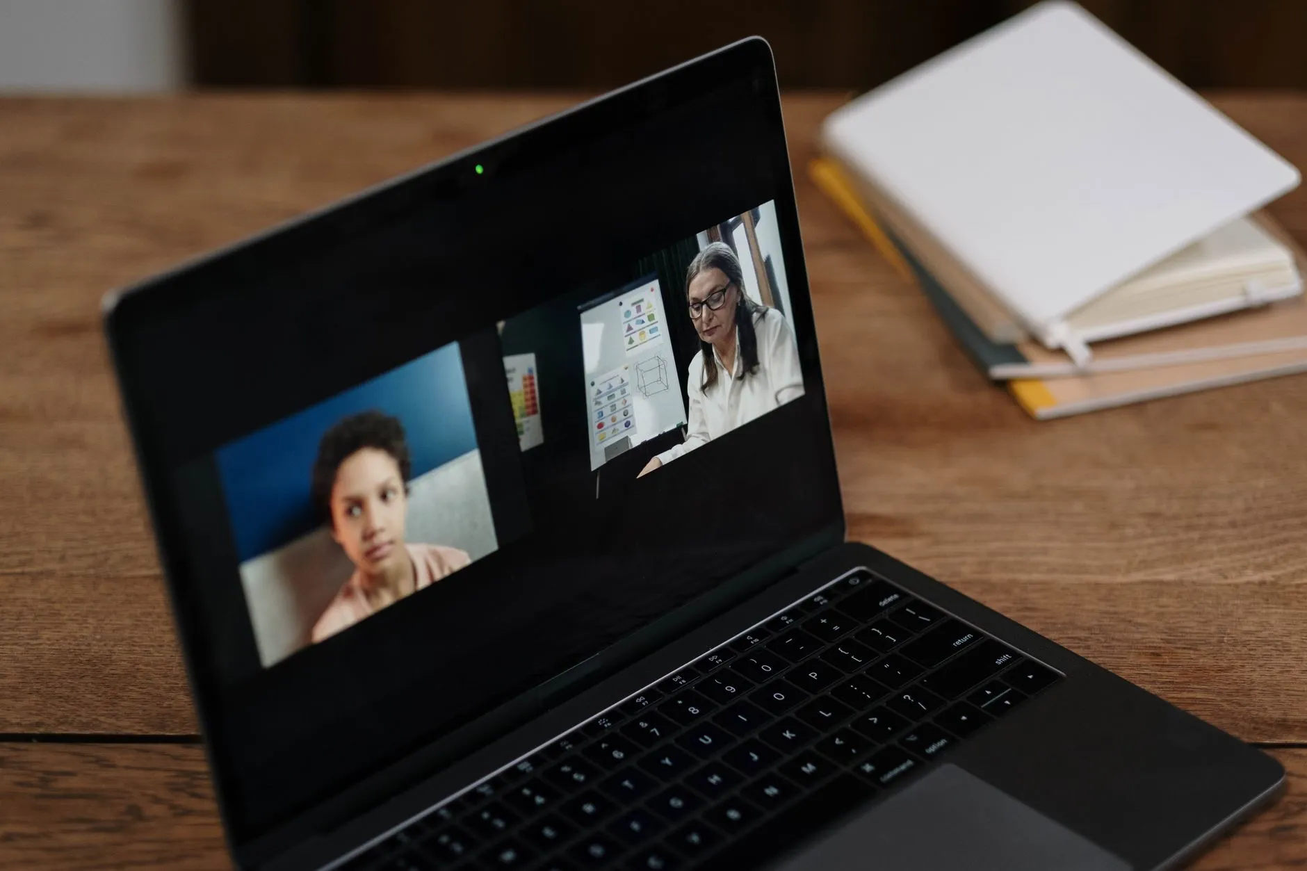 Notebook sobre uma mesa exibindo uma chamada de vídeo com duas pessoas