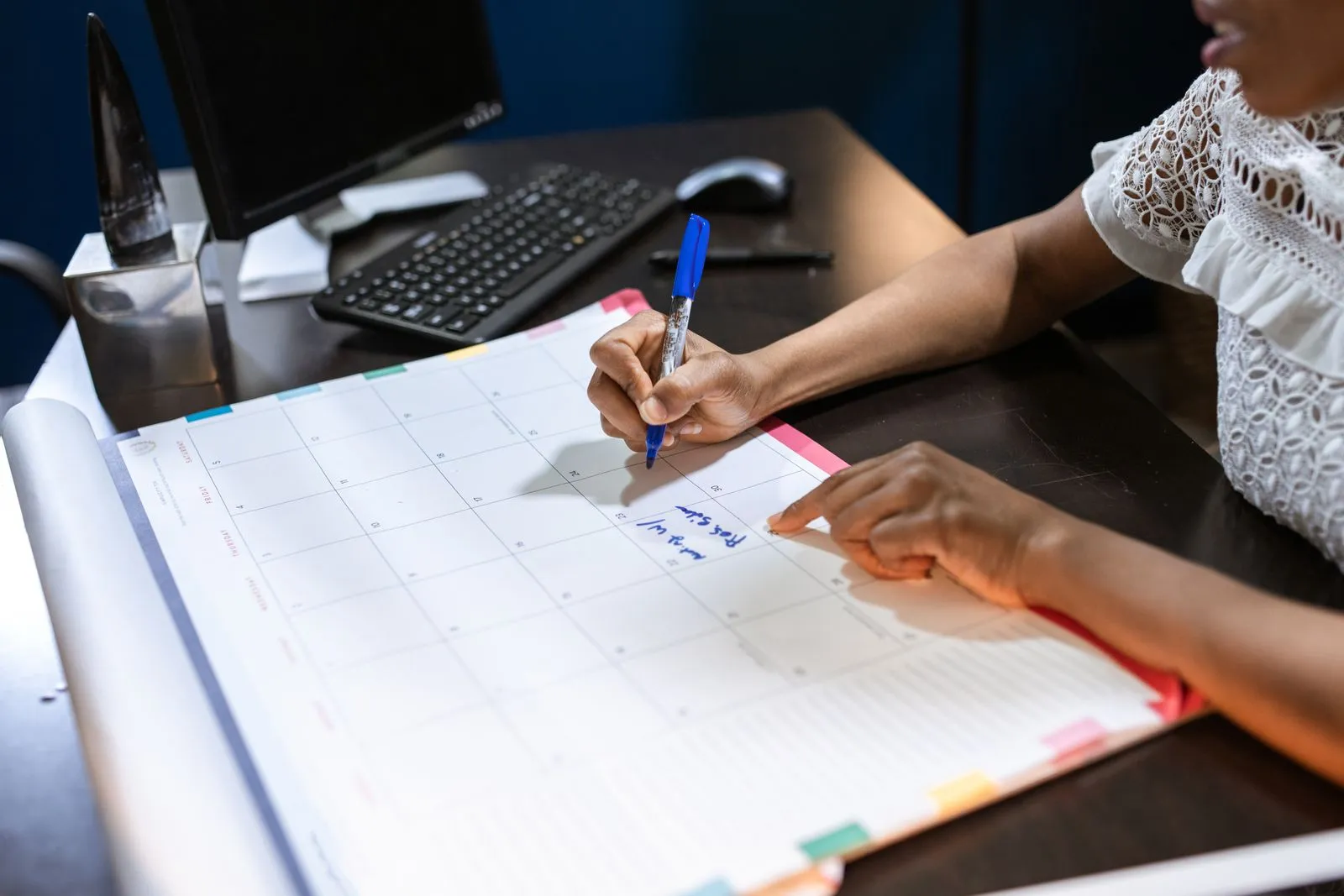 Mão marcando datas com caneta em um calendário de mesa