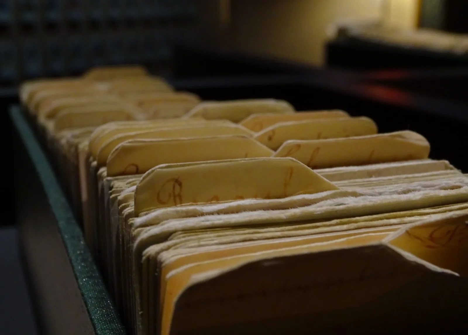 Fichário antigo com pastas de papel amareladas enfileiradas em um arquivo